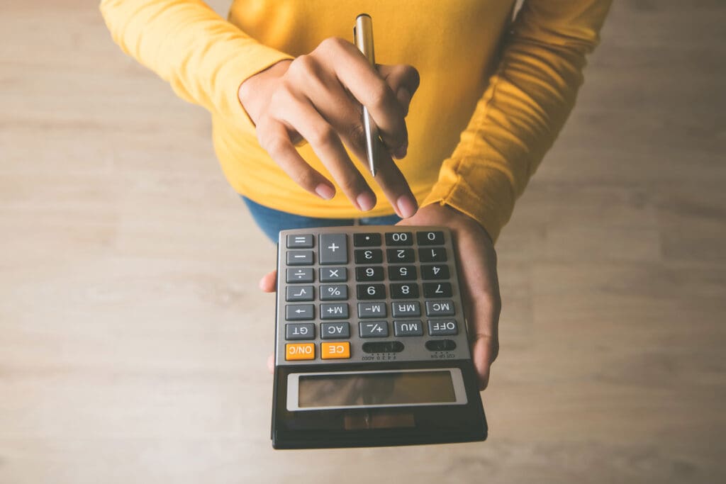 Woman using a calculator with a pen in her hand, calculating savings from rebates