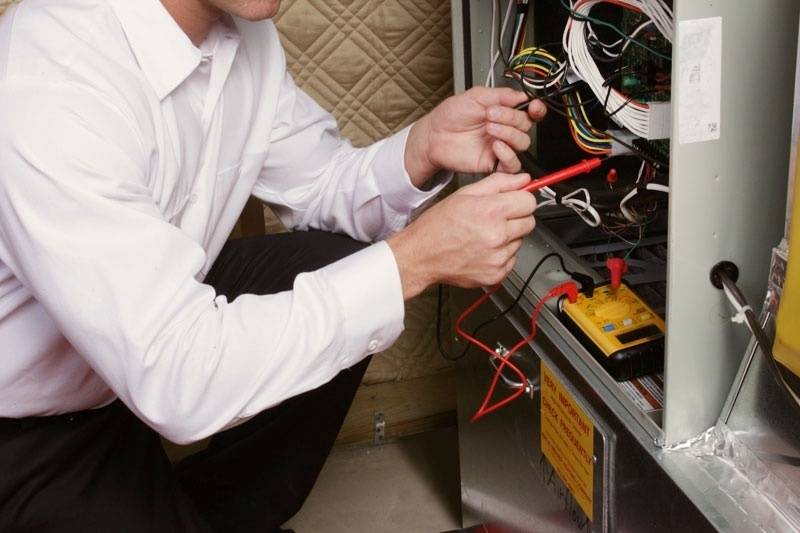 technician's hands repairing a gas furnace