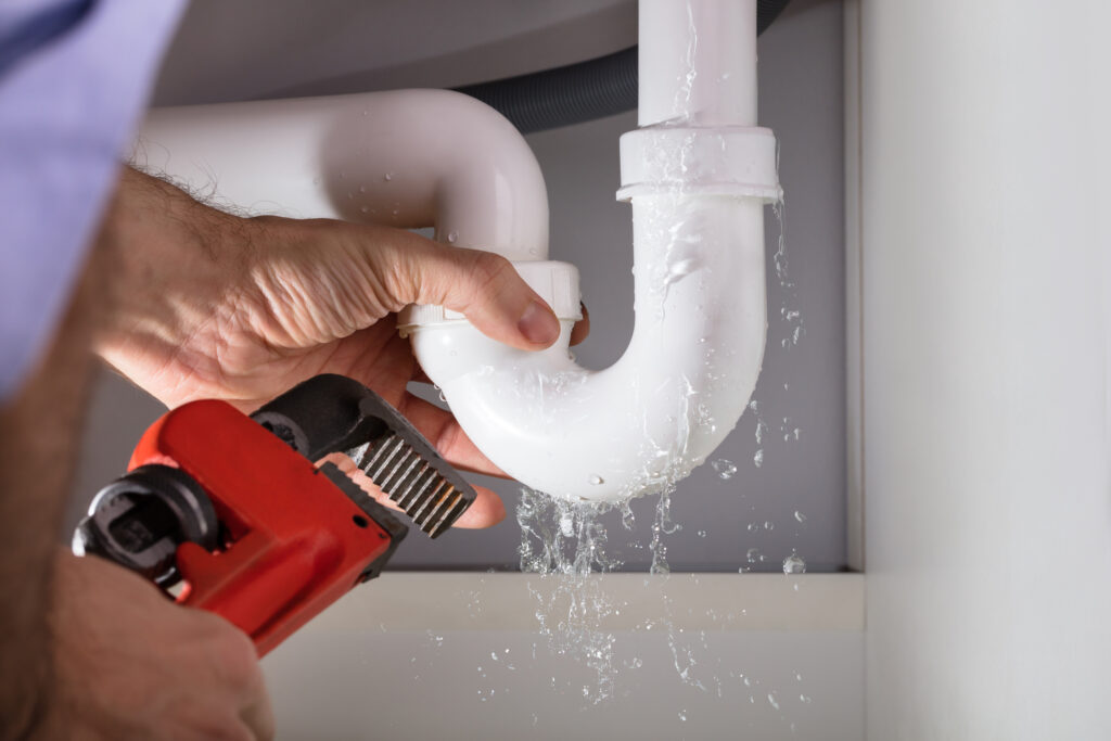 Close-up Of Classic Aire Care Plumber Fixing Sink Pipe Leak With Wrench